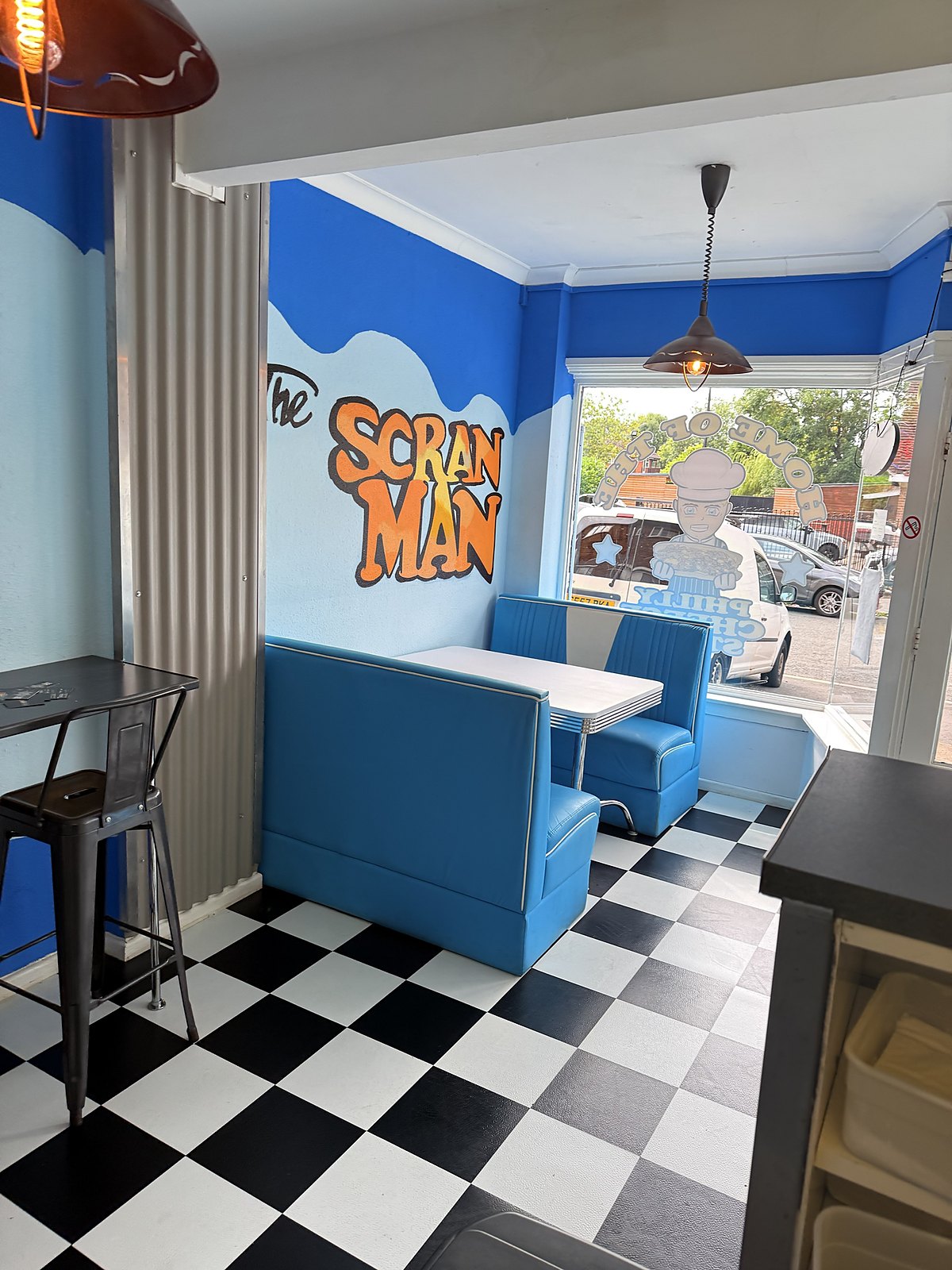 Inside The Scran Man: blue diner booths, checkerboard floor and graffiti mural